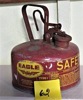 Side view of the red galvanized steel Eagle gas safety can with yellow safety instructions, showing wear and rust spots.
