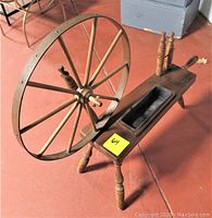 Side view of vintage wooden yarn spinner showing large wheel, turned legs, and spindle area