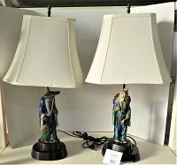 Pair of vintage chalkware Oriental men lamps with shades, showing both lamps side by side on black bases with cords and cream-colored shades, approx. 26 inches tall.