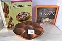Showing the glass cheese dish with its original box and the teak revolving platter with its box, items laid out for clear view.