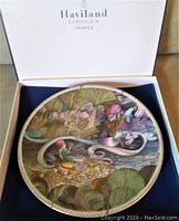 Top view of Haviland Limoges collectible plate in original box showing detailed Aladdin scene with genie and Aladdin character, surrounded by nature and palace elements.