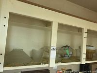 Shelved collection of various glass light shades including clear, frosted, and amber finishes