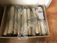 Box containing multiple cardboard tubes wrapped in plastic housing player piano rolls