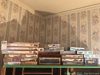 Overview of boxed Tyco HO Scale model train kits and cars and accessories stacked on shelf, various types including freight cars and accessories