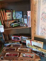 Overview of model train items and accessories on wooden shelves and dresser, showing boxes of Tyco HO scale freight cars and locomotives along with accessory packages.
