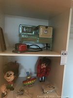 Wide view of shelf showing vintage toy oven, red toaster, Mickey Mouse toys, puppet, and small additional toys