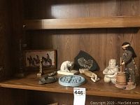 Wide view of Indigenous figurines and totem pole miniatures on wooden shelf.