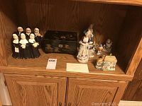 Overview of all figurines and music box on wooden shelf
