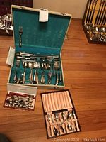 Overview image showing three cases containing silver plated cutlery sets, each case open displaying utensils arranged inside.