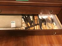 Drawer open showing multiple knives with ivory handles in original packaging and loose.