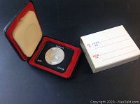 1972 Canadian silver dollar coin in hinged display case with outer cardboard sleeve.