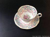 Cup and saucer with Queen Anne Royal Bridal Gown pattern, showing floral and bow decorations with gold trim.