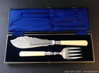 Full set of the silver plated serving knife and fork with bone handles in original lined case showing blue velvet insert and silk interior lid.