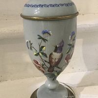 Close-up of lamp body showing hand painted bird and flower details on blue porcelain background with brass trim.