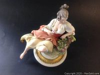Front angle view of the Capodimonte figurine showing the seated peasant girl with detailed face, dress, and base.