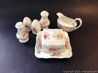 Copeland Spode 'Fairy Dell' china set with two salt and pepper sets, creamer, and butter dish from a front angle showing floral pattern.