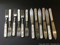 All 12 pieces including six forks and six knives displayed side by side showing mother of pearl handles and silver plate blades and tines.