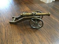 Side view of 12-inch bronze miniature field cannon on two-wheeled carriage