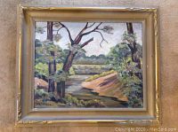 Full view of framed oil painting depicting a Canadian country landscape with trees and stream.