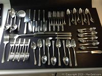 Full spread of 63 COMMUNITY silverplate flatware pieces arranged on a flat surface, showing multiple types of forks, spoons, knives, serving utensils all with engraved floral design on the handles.