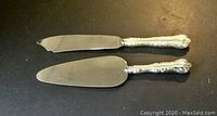 Top down photo showing both cake server and knife with ornate Louis XV style handles and polished silver blades.