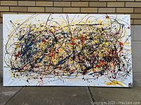 Full front view of the painting leaning against a brick wall outdoors