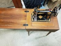 Full view of the Singer sewing machine in the wooden cabinet with fold-out table extension