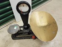 Front angle view of the vintage scale showing dial display, large brass catch bin, and smaller metal tray