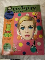 Front cover of 1967 Twiggy paper doll book featuring large illustrated portrait of Twiggy, colorful polka dot design, and smaller Twiggy figure illustrations