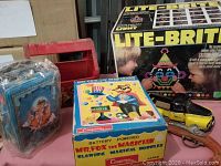 Assortment including sealed tin, red plastic caddy, Mr. Fox box, yellow car, cap gun, Lite-Brite box