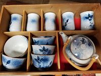 Full view of tea set in wooden box showing teapot, tea cups, and bowls.