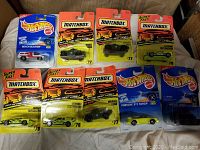 Sealed Matchbox and Hot Wheels die-cast cars laid out on a surface showing various models including Beach Blaster and Porsche 911 Targa.