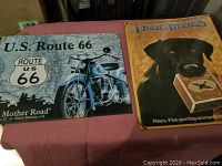 Photo shows U.S. Route 66 metal sign with blue motorcycle and True Blues Peters ammunition sign with black dog.