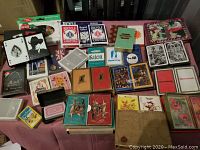 Wide arrangement of 49 decks of playing cards, showing variety of brands and themes, some sealed in original packaging.