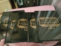 Five black hardcover Lionel Richie Tuskegee Tour books stacked side by side showing gold lettering on covers.