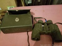 Full view of olive green Sears Discoverer binoculars and matching carrying case with shoulder strap on pink surface