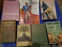 Shows assorted vintage books including 'Cadette', 'Captains Courageous' by Rudyard Kipling, and 'Boy Scout Handbook' among others.