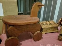 Wooden duck pull toy with wheels and a neck peg, natural wood finish.