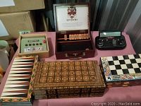 Wide view showing two decorative wooden game boxes, a battery-operated chess and poker console, chess and backgammon boards