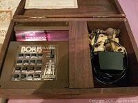 Wooden case with Boris Master chess computer, chess pieces, and power plug, showing keypad and display