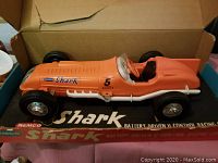 Photo of orange Remco Shark tether racing car in original box showing side view.