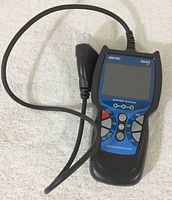 Full view of the Innova 3040 CAN OBD II Reader including screen, buttons, and attached cable with vehicle connector.