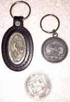 Top view of the front side of the NRA leather keychain with metal medallion, round NRA metal keychain, and Department of Treasury metal medal
