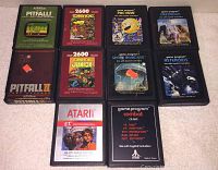 Photo showing 11 Atari 2600 video game cartridges featuring titles Pitfall, Donkey Kong, Pac-Man, Defender, Pitfall II, Donkey Kong Junior, Space Invaders, Asteroids, E.T., and Combat laid out on a surface.