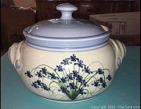 Front view of the bean pot showing the floral decoration and lid.