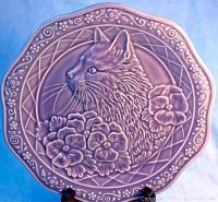 Front view of a purple decorative plate with an embossed cat profile and floral details
