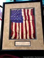 Framed print of American flag with matted border and visible folds in the fabric representation.