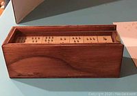Wooden dominoes tiles visible inside the wooden box