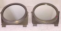 Front view of two round industrial metal frame swivel mirrors, showing reflective surfaces and mounting bracket sides.