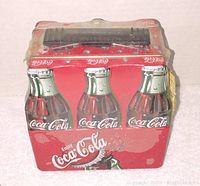 Front view of the Coke lunch box tin showing six bottle design and handle